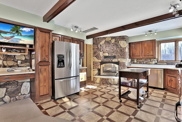 10834 178th Cir NW, Elk River, MN 55330 - kitchen featuring appliances with stainless steel finishes, track lighting, light countertops, a stone fireplace, and beam ceiling