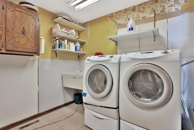 10834 178th Cir NW, Elk River, MN 55330 - laundry area featuring washer and clothes dryer, cabinet space, light tile patterned flooring, tile walls, and wainscoting