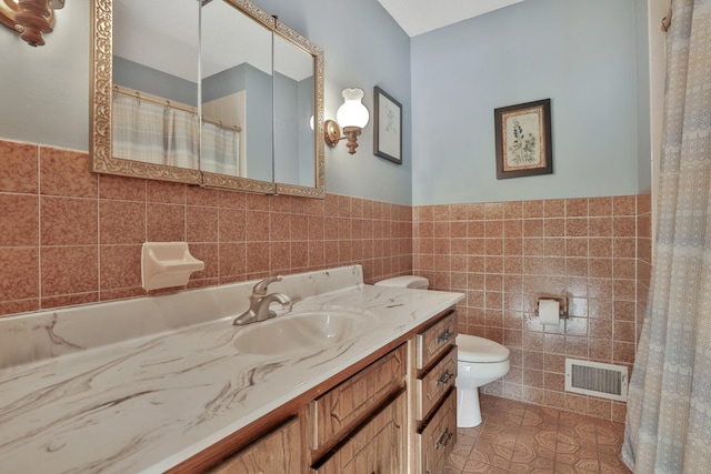 10834 178th Cir NW, Elk River, MN 55330 - full bath with tile walls, tile patterned floors, toilet, a wainscoted wall, and vanity