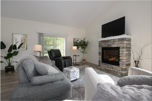 living room featuring a stone fireplace, hardwood / wood-style floors, and vaulted ceiling