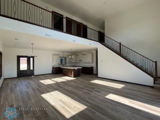 1204 Lincoln, Lisbon, ND 58054 - unfurnished living room featuring a towering ceiling, stairs, and wood finished floors