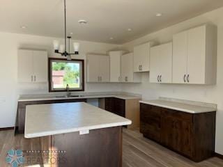 1204 Lincoln, Lisbon, ND 58054 - kitchen with a center island, white cabinets, a sink, and wood finished floors