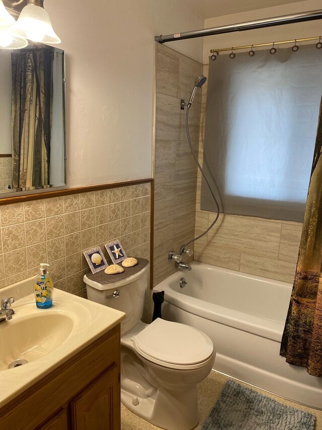 full bathroom featuring vanity, shower / bathtub combination with curtain, tasteful backsplash, tile walls, and toilet