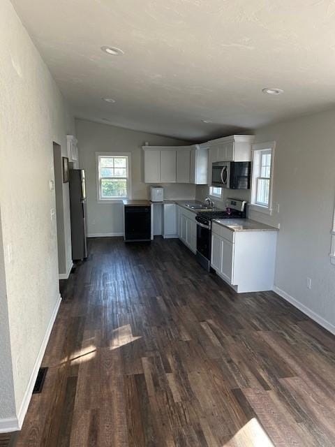 kitchen with lofted ceiling, white cabinetry, dark wood-type flooring, and stainless steel appliances