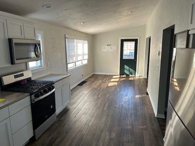 kitchen featuring white cabinets, appliances with stainless steel finishes, dark hardwood / wood-style floors, and lofted ceiling