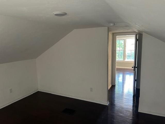 additional living space featuring lofted ceiling and dark hardwood / wood-style floors