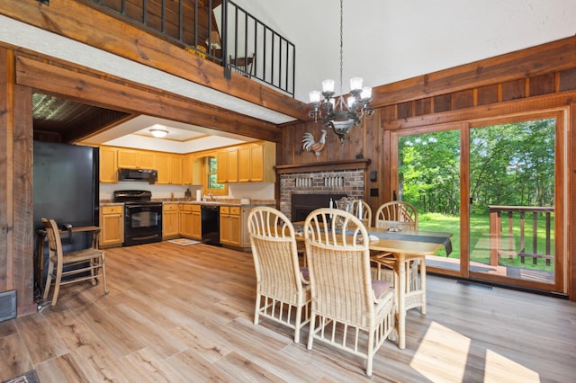 dining room with a chandelier, wooden walls, light hardwood / wood-style floors, and a high ceiling