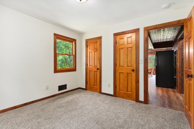 unfurnished bedroom with a textured ceiling and dark carpet