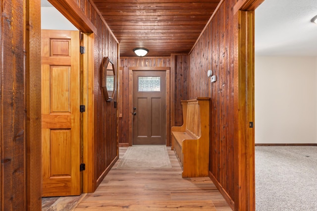 doorway to outside with light hardwood / wood-style floors, wooden ceiling, and wooden walls