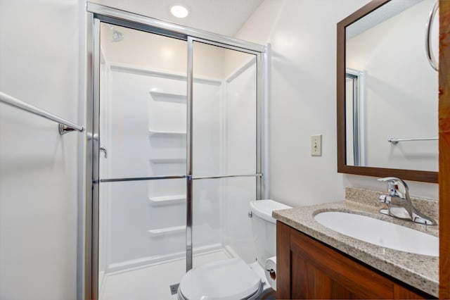 bathroom featuring a shower with door, vanity, and toilet