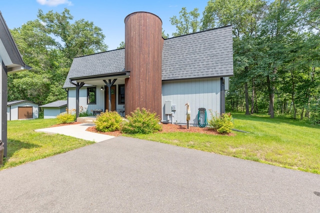 view of front of home with an outdoor structure, a front lawn, and a garage