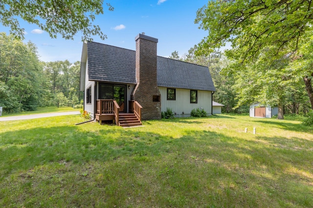 rear view of property with a yard and a storage shed