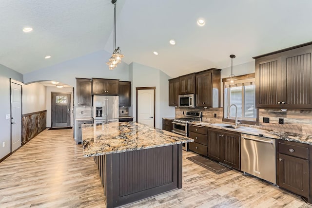 kitchen with pendant lighting, stainless steel appliances, light wood-type flooring, a center island, and sink