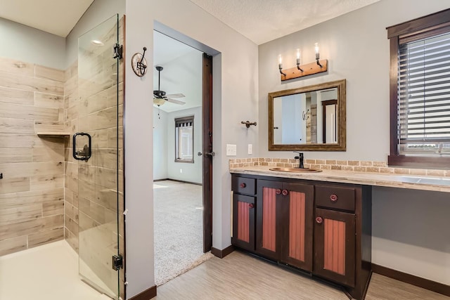 bathroom with walk in shower, a textured ceiling, vanity, and ceiling fan