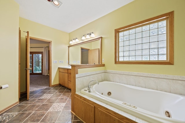 full bath with baseboards, vanity, and a jetted tub