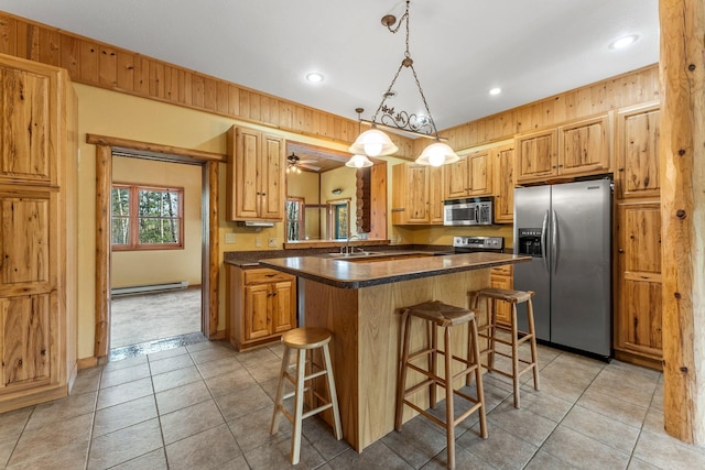 kitchen with a breakfast bar area, appliances with stainless steel finishes, pendant lighting, and wood walls