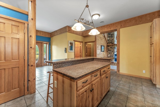 kitchen featuring a breakfast bar, a center island, dark tile patterned flooring, and pendant lighting