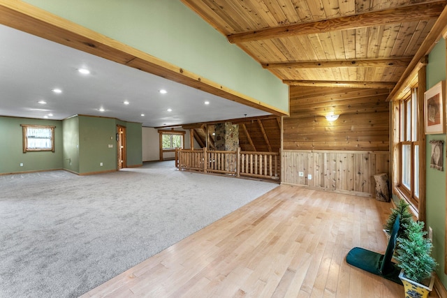 unfurnished room with wooden ceiling, a wealth of natural light, wooden walls, and lofted ceiling with beams