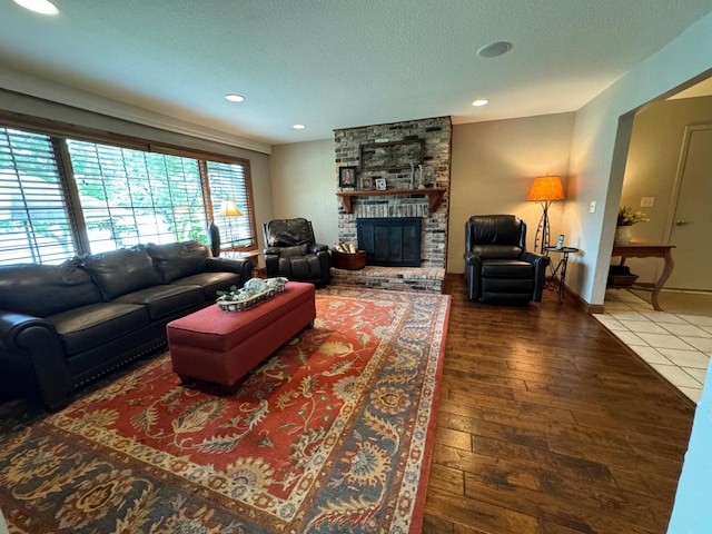 living room with a brick fireplace, hardwood / wood-style floors, and a textured ceiling