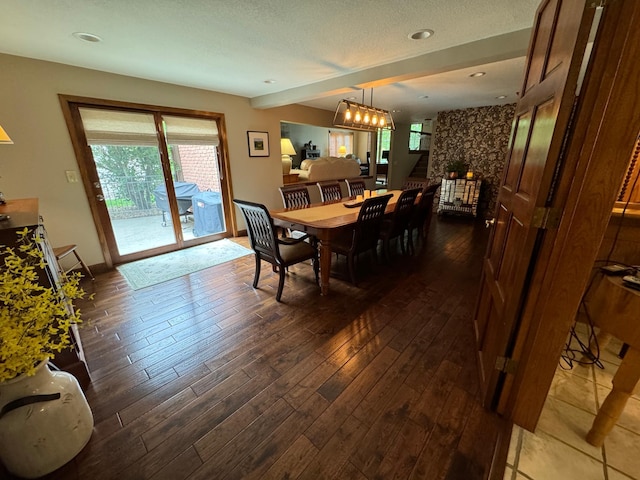 dining area featuring an inviting chandelier, dark wood-type flooring, and a textured ceiling