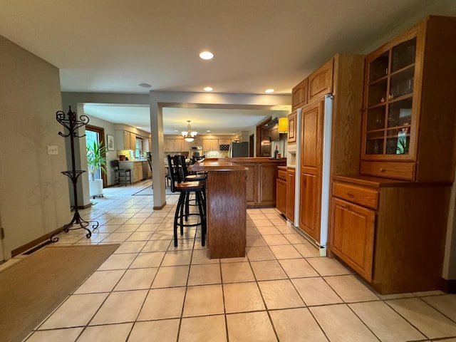 kitchen featuring a kitchen island, a breakfast bar area, refrigerator, and light tile patterned floors