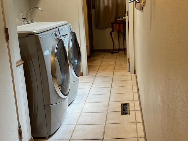 clothes washing area featuring washing machine and dryer and light tile patterned floors