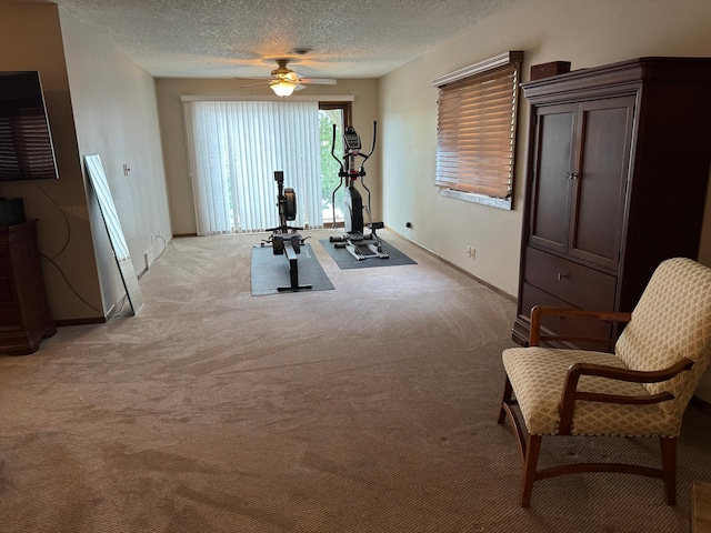 exercise room featuring a textured ceiling, light colored carpet, and ceiling fan