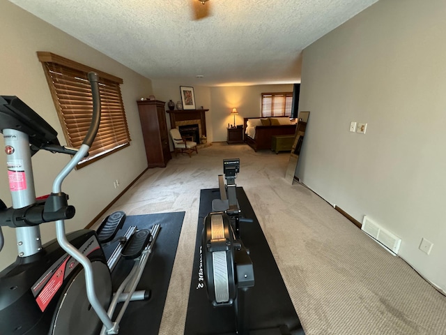 exercise room featuring light carpet and a textured ceiling