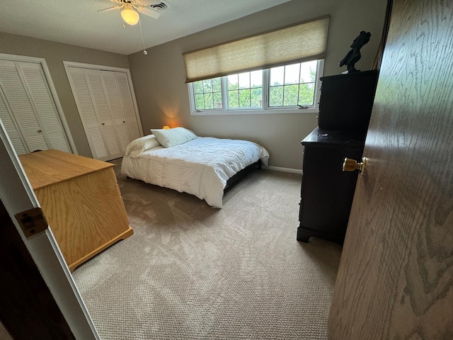 bedroom with multiple closets, carpet, and ceiling fan