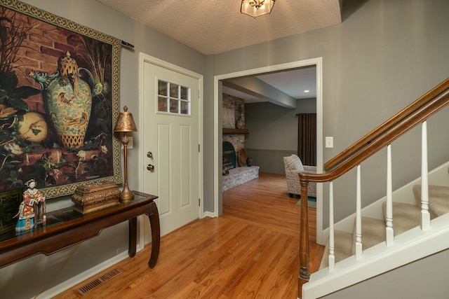 entryway with a fireplace, a textured ceiling, and light hardwood / wood-style flooring