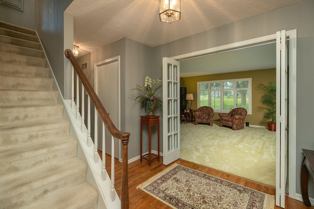 entrance foyer featuring hardwood / wood-style flooring, a textured ceiling, and french doors