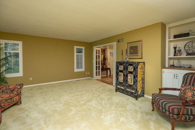 living area with a textured ceiling, built in features, and light carpet