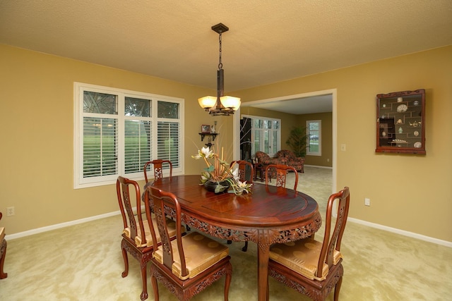 dining space featuring a textured ceiling, an inviting chandelier, and light carpet