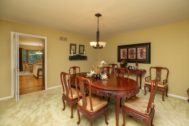 dining space featuring a textured ceiling, an inviting chandelier, and light carpet