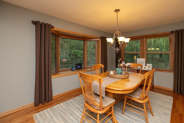 dining space featuring a textured ceiling, light hardwood / wood-style flooring, and an inviting chandelier