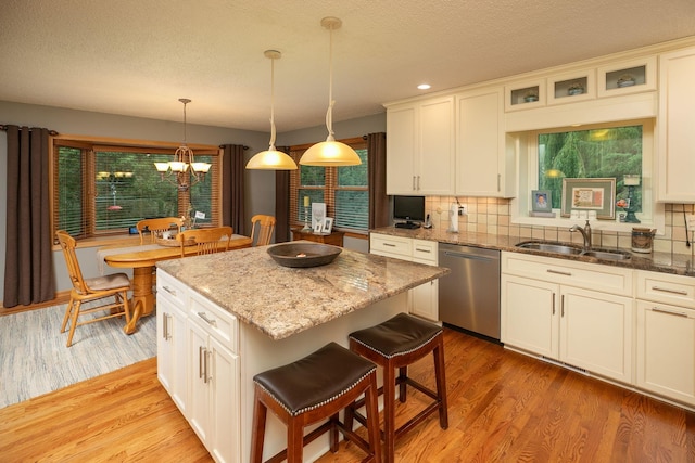 kitchen with dishwasher, light hardwood / wood-style floors, decorative backsplash, a kitchen island, and sink