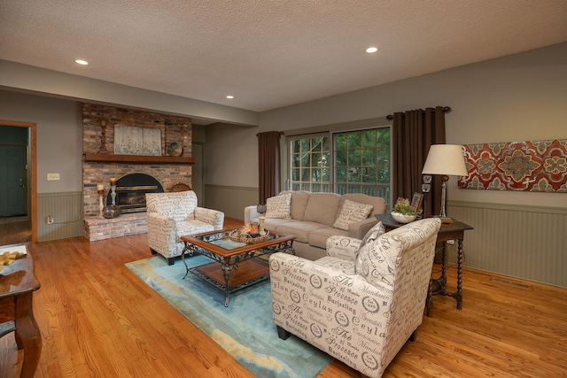 living room with a fireplace, a textured ceiling, and light hardwood / wood-style floors