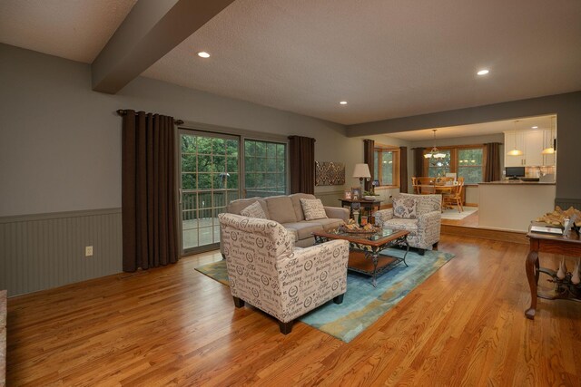 living room featuring plenty of natural light, beamed ceiling, and light hardwood / wood-style flooring