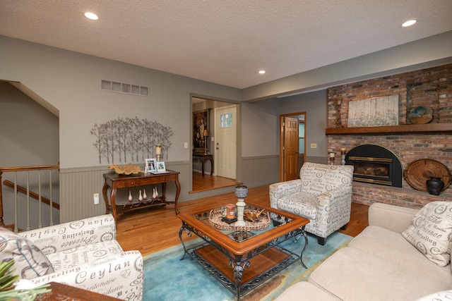 living room featuring a textured ceiling, hardwood / wood-style flooring, and a fireplace