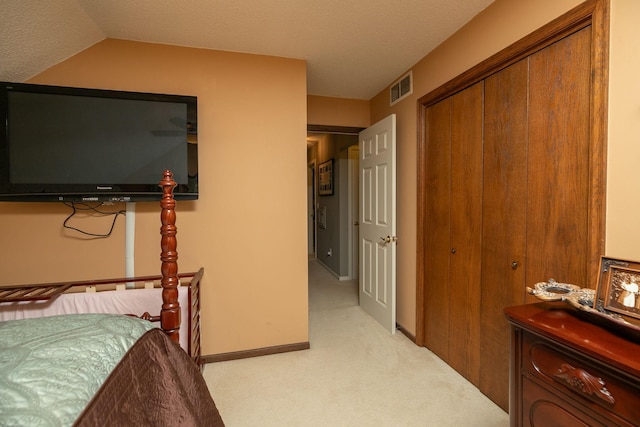 bedroom with a closet, a textured ceiling, and light colored carpet