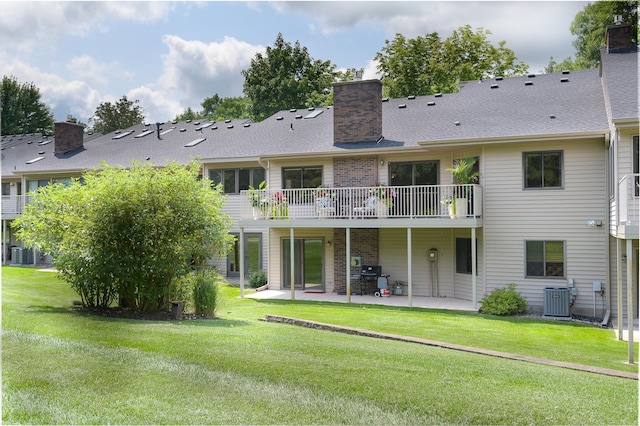 rear view of property featuring a balcony, central air condition unit, a lawn, and a patio