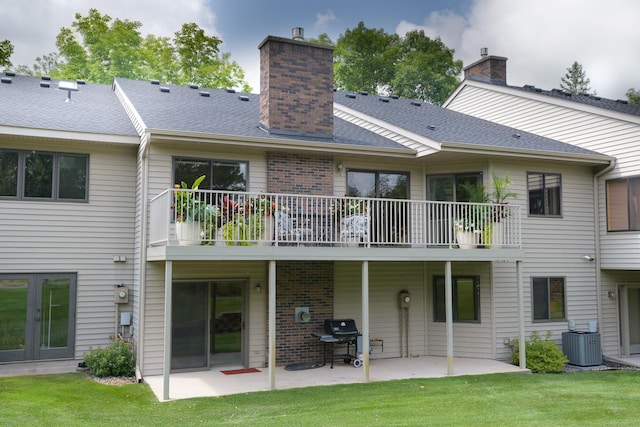 rear view of property featuring cooling unit, a yard, a patio area, and a balcony