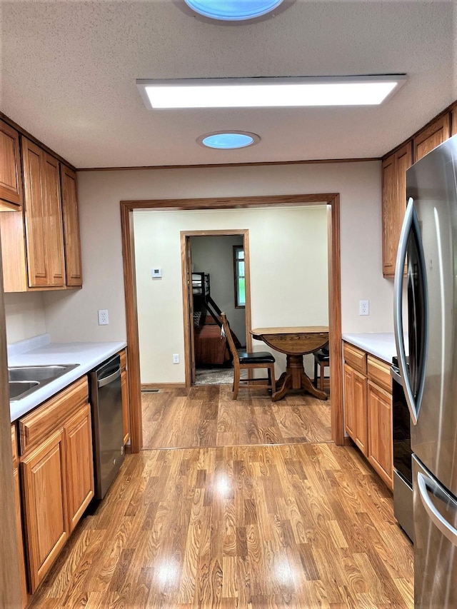 kitchen with sink, appliances with stainless steel finishes, light hardwood / wood-style flooring, and a textured ceiling