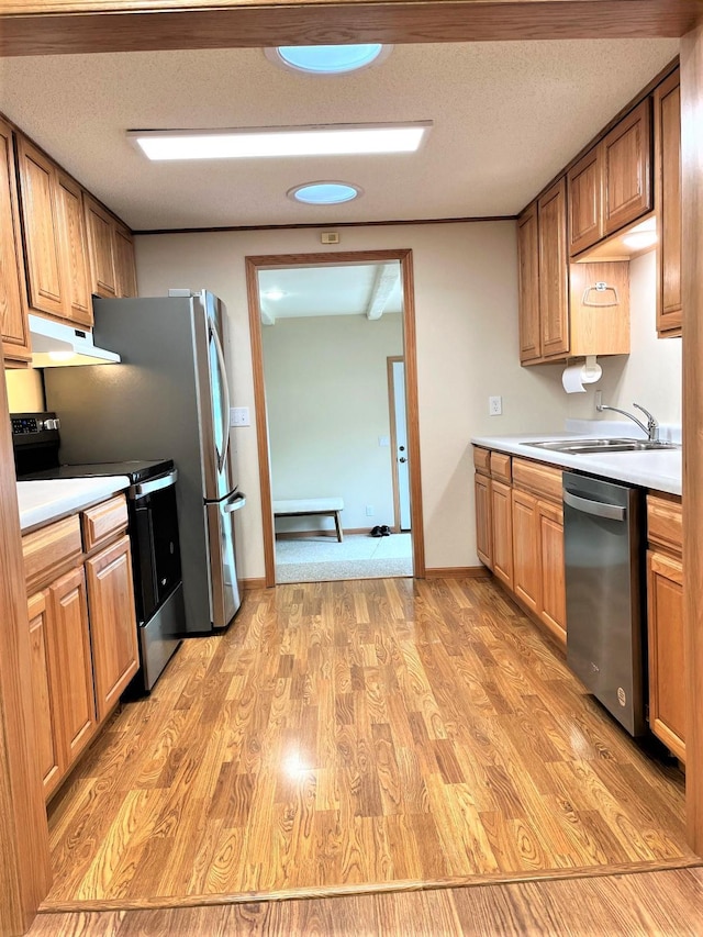 kitchen with sink, a textured ceiling, stainless steel appliances, and light wood-type flooring