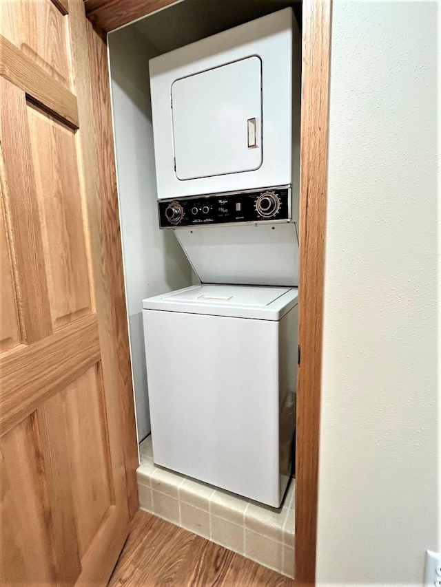 clothes washing area featuring light hardwood / wood-style floors and stacked washer / drying machine