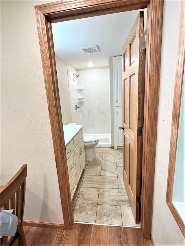 bathroom with vanity, toilet, and tiled shower