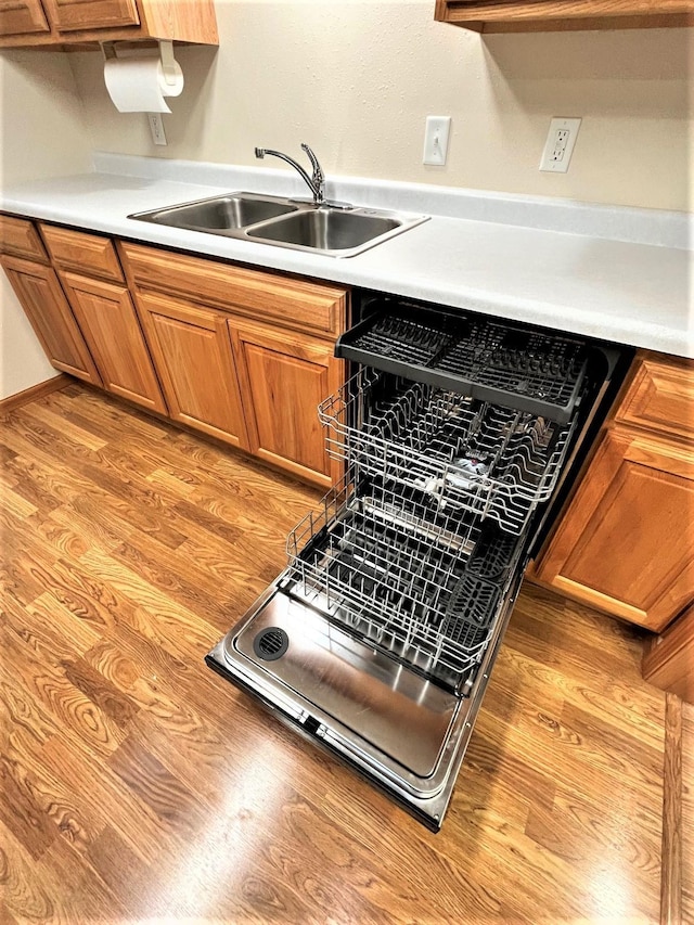 kitchen featuring dishwashing machine, sink, and light wood-type flooring