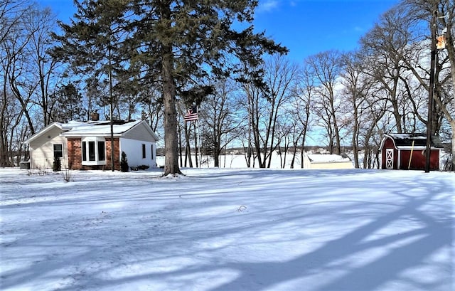 yard covered in snow featuring a storage unit and an outbuilding