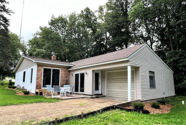 back of house with a patio, a shingled roof, a lawn, and a chimney