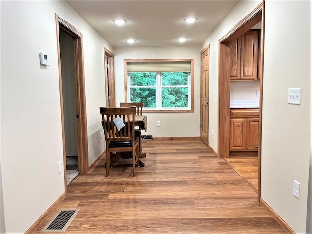 hallway with light wood-style floors and visible vents